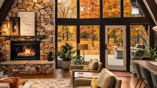 A spacious loft with a stone fireplace, large windows, and a cozy seating area. - Maple Bluff Escape | A-Frame w/ Theater + Hot Tub (Stevens Point)