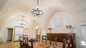 A dining area with a wooden table, chairs, a chandelier, and a decorative wall piece.