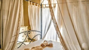 A bed with a canopy, a bedside table, and a dresser in a room.