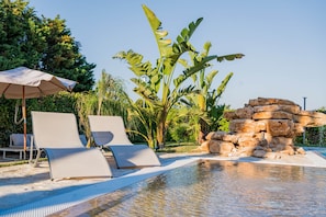 Uma área de piscina com espreguiçadeiras e uma estrutura de pedra.