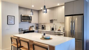 A modern kitchen with a central island, stainless steel appliances, and pendant lighting. - Cozy Sunset | Amazing views | Private hottub (Revelstoke)