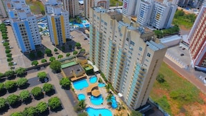 A high-rise residential building with multiple balconies, a rooftop pool area, and surrounding greenery. - Temporada Thermas Place Suítes Caldas Novas (Caldas Novas)