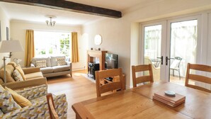 A living room with a sofa, a wooden dining table, and a television. - The Old Police House (Saltburn-by-the-Sea)