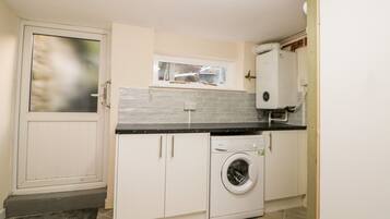 A compact kitchen with a built-in washer and dryer, a window above the sink, and a door with a frosted glass panel.
