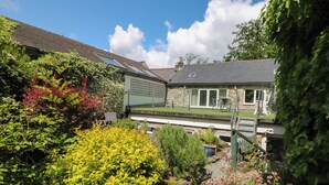 A residential property with a stone house, a garden with various plants, and a patio area. - Wilson Eyre Cottage (Hope Valley)