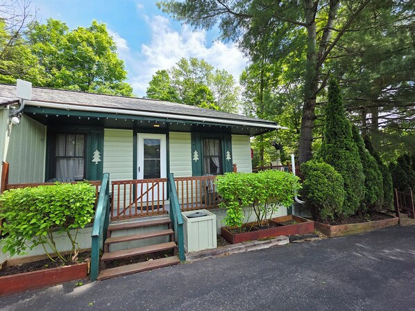 A small, single-story house with a green exterior and a porch with steps leading to the front door. - Adirondack Sunrise Motel and Cabins (Lake George)