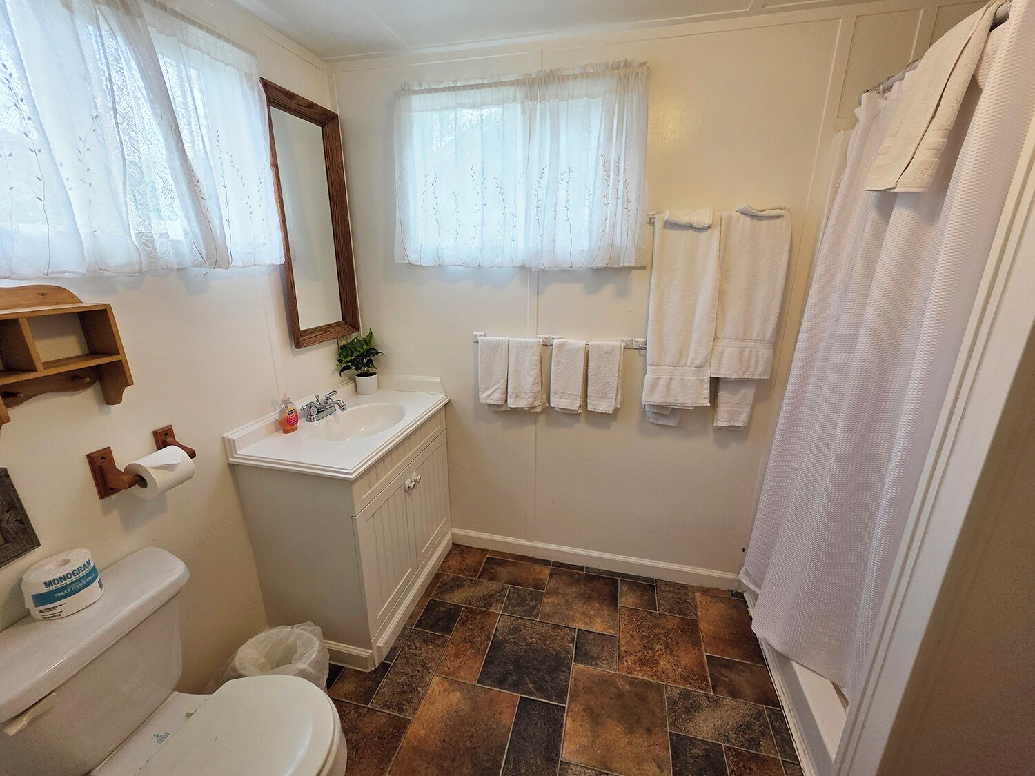 Une salle de bain équipée de toilettes, d’un lavabo, d’un miroir et d’une douche.