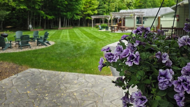 A patio area with a stone floor, green lawn, and outdoor furniture. - Adirondack Sunrise Motel and Cabins (Lake George)