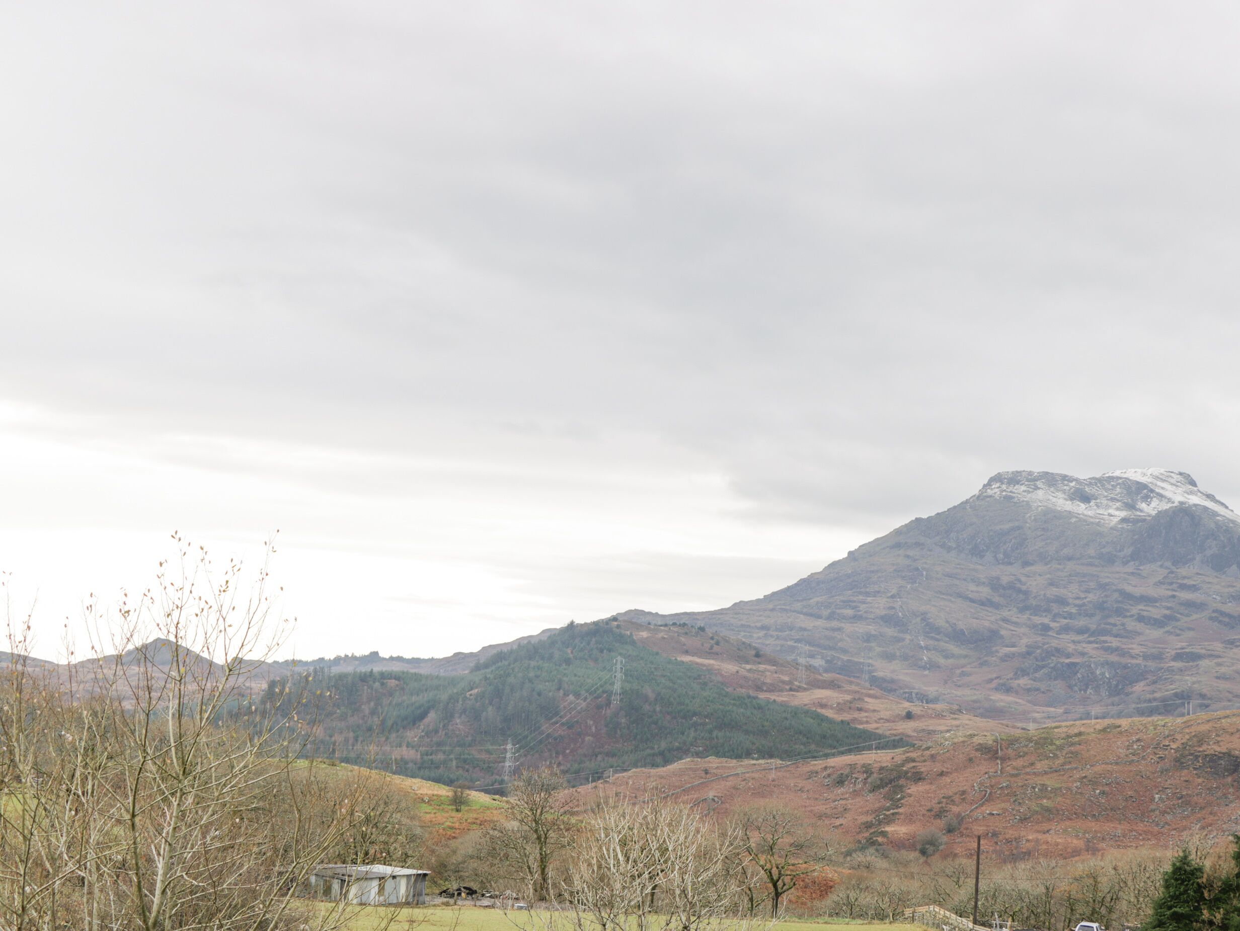 A mountainous landscape with a small building in the foreground.