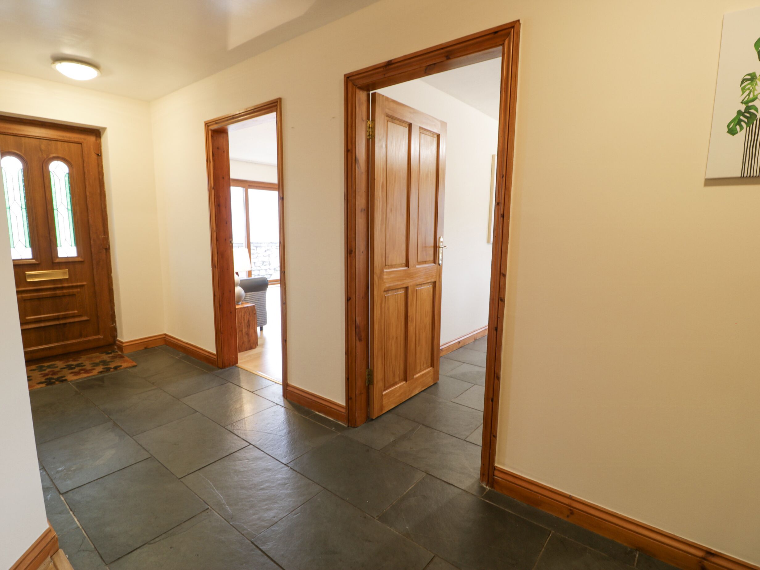 A hallway with a wooden door, a glass door, and a tiled floor.