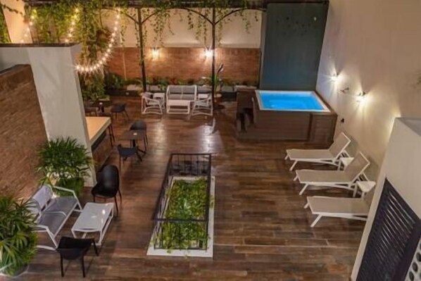 An indoor patio with wooden flooring, a pool, lounge chairs, and tables.