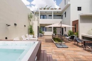 A modern outdoor pool area with lounge chairs and a hot tub. - Loft 201 - w/balcony - Daily Cleaning (Santo Domingo)
