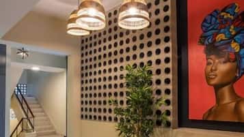 Un interior moderno con una escalera, una lámpara fijada a la pared y una obra de arte enmarcada.