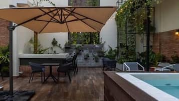 Un patio al aire libre con piscina, mobiliario y una escalera que conduce a un nivel superior.