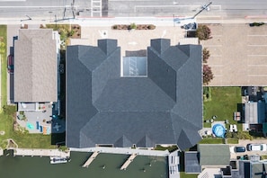 An aerial view of a building with a large parking lot, a swimming pool, and a small dock area.
