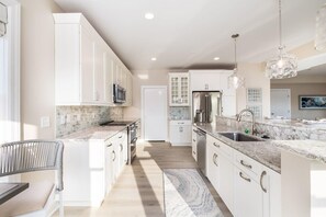 A modern kitchen with white cabinets, a marble countertop, and stainless steel appliances. - Luxurious Bay/ Ocean view Splendor 4 BRS elevator (Ocean City)
