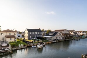 Un quartier résidentiel bordé de maisons le long d’un canal, avec un quai où est amarré un bateau et une pelouse verdoyante.