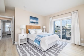 A bedroom with a bed, nightstands, a window with curtains, and a city view.