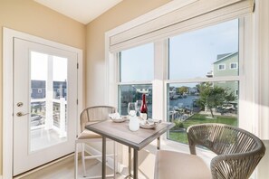 A balcony with a table and chairs, a bottle of wine, and a view of a marina.