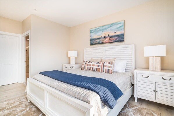 A bedroom with a large bed, two bedside tables, a nightstand, a painting on the wall, and a door to the left. - Luxurious Bay/ Ocean view Splendor 4 BRS elevator (Ocean City)
