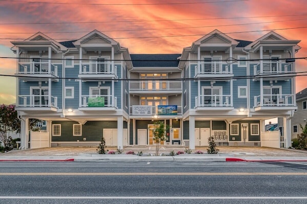 Une rangée de maisons de ville à trois étages, dotées d’une entrée centrale, chacune ayant un balcon et un garage.