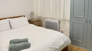 A bedroom with a bed, a nightstand, a heater, a wardrobe, and a chandelier. - Cosy 1bed in Wembley  (Wembley)