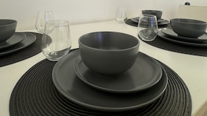 A dining table set with black bowls and glasses, surrounded by black placemats. - Cosy 1bed in Wembley  (Wembley)