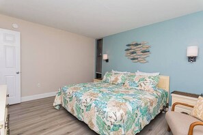 Une chambre à coucher avec un lit, une table de chevet, une lampe et un élément décoratif mural.