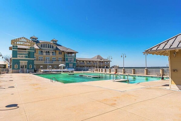 A resort with a large pool, a building with multiple balconies, and a clear view of the ocean. - Sunset Island Townhouse - 5 Bdr/ Sleeps 12/ pool (Ocean City)
