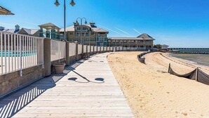 A wooden boardwalk leading to a beach with a building in the background.