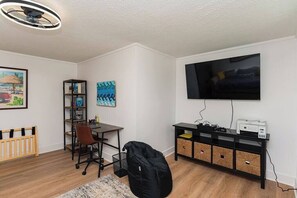 A room with a desk, chair, bookshelf, TV, and storage unit. - "The Hive"-Downtown Berlin, 4 BR, Sleeps 8, 2 Bath (Berlin)