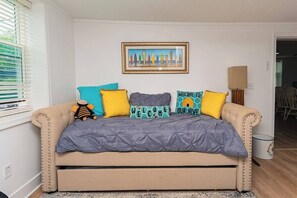 A beige sofa with a grey quilted cover, multiple cushions, and a framed painting above. - "The Hive"-Downtown Berlin, 4 BR, Sleeps 8, 2 Bath (Berlin)