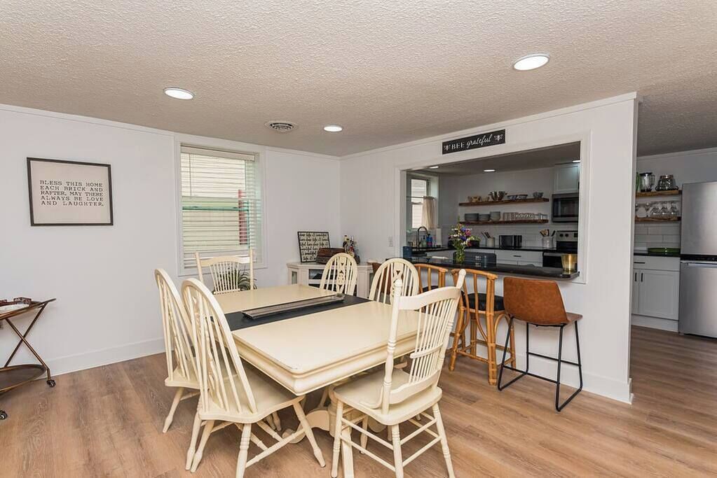 Un coin repas avec une table et des chaises, une cuisine en arrière-plan et un panneau indiquant : « Cadeaux offerts ».