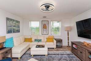 A living room with a sectional sofa, a coffee table, a TV, and a lamp. - "The Hive"-Downtown Berlin, 4 BR, Sleeps 8, 2 Bath (Berlin)
