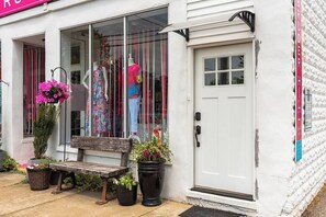A storefront with mannequins displaying colorful clothing, a bench, and potted plants outside. - "The Hive"-Downtown Berlin, 4 BR, Sleeps 8, 2 Bath (Berlin)
