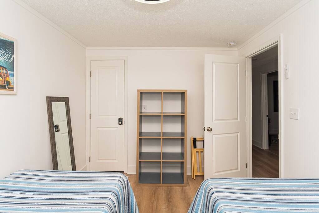 Une chambre avec deux lits, une armoire et un miroir.