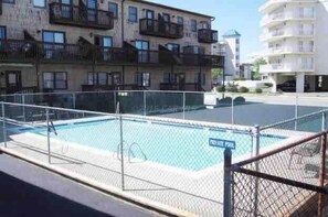 Une piscine entourée d’une clôture, avec un panneau indiquant : « PISCINE PRIVÉE ».
