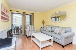 Una sala de estar con sofá, sillón, mesa de centro y televisor.