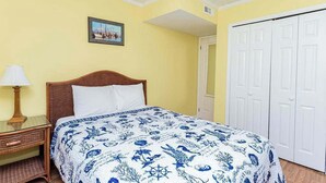 A bedroom with a bed, a nightstand, a lamp, a framed picture on the wall, and a white door. - Downtown Family Value - Sleeps 6 - with Pool (Ocean City)