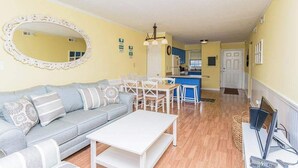 A living room with a sofa, coffee table, and dining area with chairs. A kitchen is visible in the background. - Downtown Family Value - Sleeps 6 - with Pool (Ocean City)