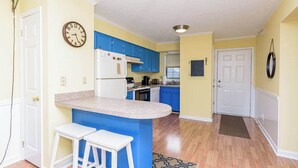 A kitchen with blue cabinets, a white refrigerator, and a clock on the wall. - Downtown Family Value - Sleeps 6 - with Pool (Ocean City)