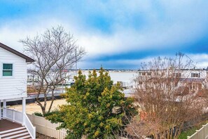A residential area with a white house, a tree, and a body of water in the background.
