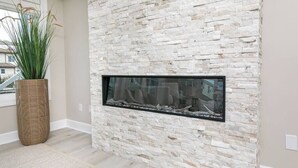 A stone wall with a built-in fireplace and a large potted plant.