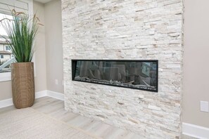 A stone wall with a built-in fireplace and a large potted plant.