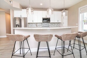 A modern kitchen with white cabinets, stainless steel appliances, and a central island with bar stools.