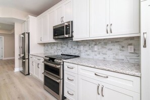 A modern kitchen with white cabinets, stainless steel appliances, and a granite countertop. - Bayside Splendor - 3BR, 3BA/ boat slip (Ocean City)