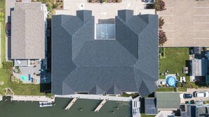 An aerial view of a building with a parking lot, a swimming pool, and a small garden area.