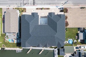An aerial view of a building with a parking lot, a swimming pool, and a small garden area.