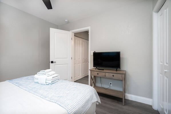 A hotel room with a bed, a television on a wooden stand, and a door leading to another room. - Lovely 1 bedroom rental unit 5 minutes to downtown (St. Petersburg)