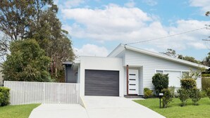 A modern two-story house with a garage, a fenced driveway, and a well-maintained lawn. - Tallwood By The Sea in Mollymook (Mollymook)